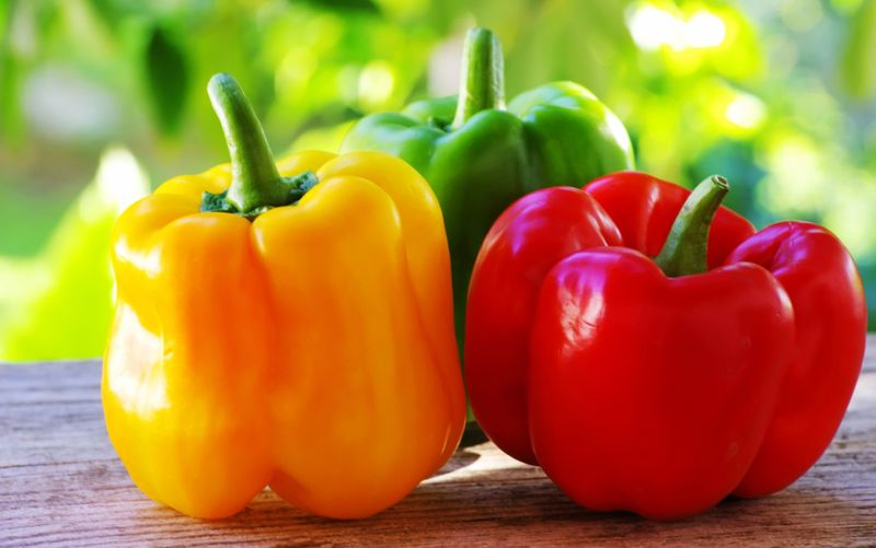 red, yellow and green pepper on table,green background