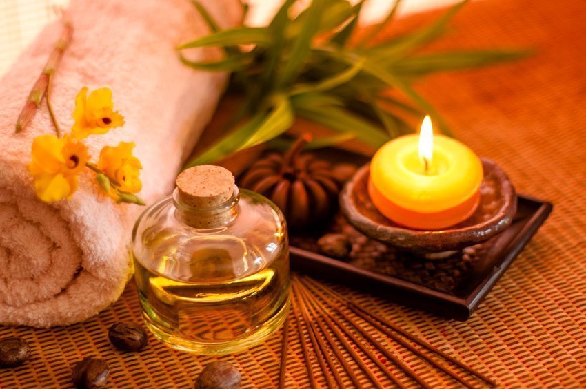 Essential oil bottles, towels, candle and flower in health spa for spa treatment. [Focus at the oil bottle]