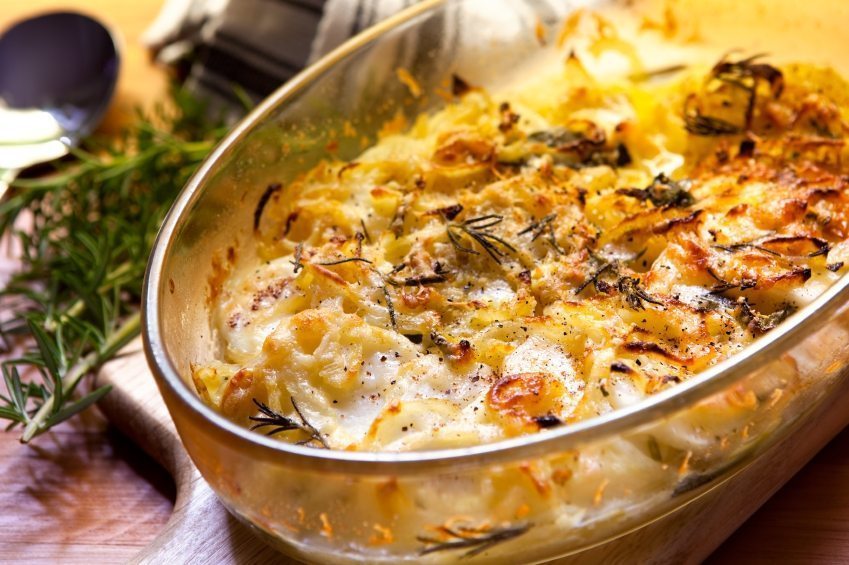 Potato and onion gratin with rosemary, in warm light.