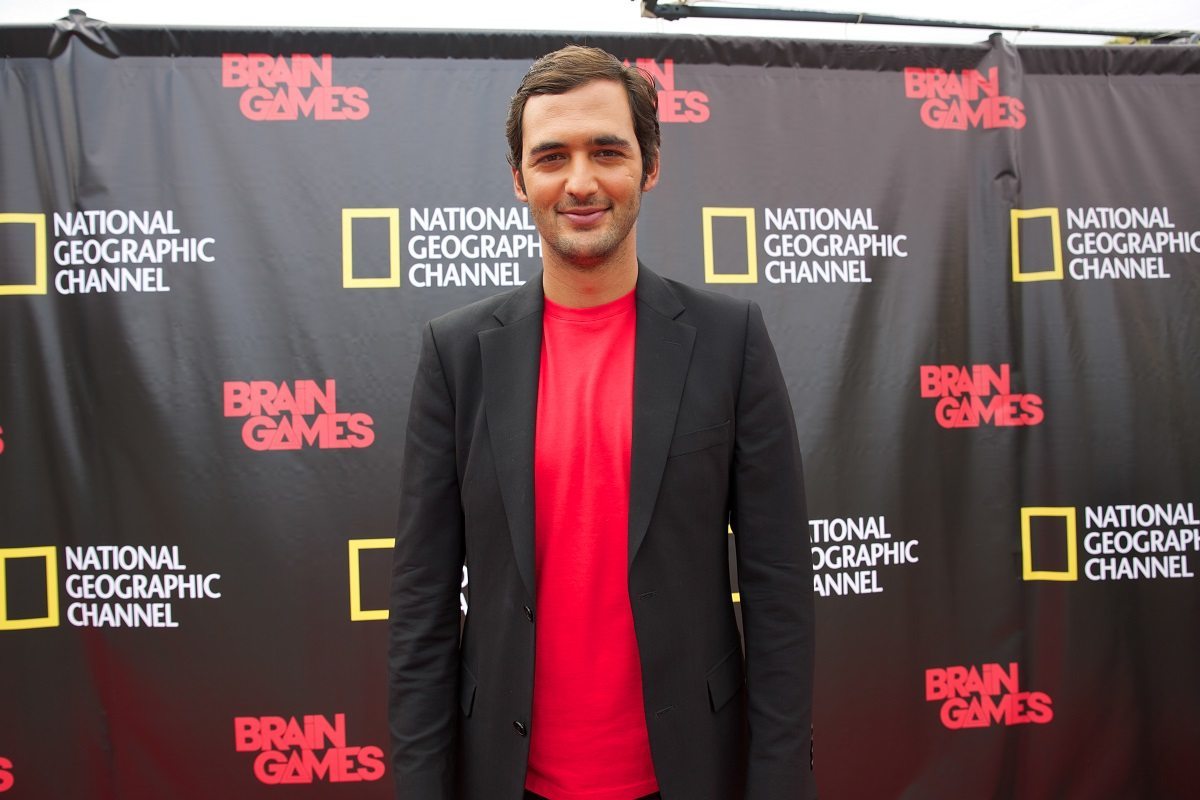 NEW ORLEANS, LA.- Jason Silva standing in front of a step & repeat covered in the National Geographic Channel and Brain Games logos.  (Photo Credit: NG Studios/Chris Van Cleef)