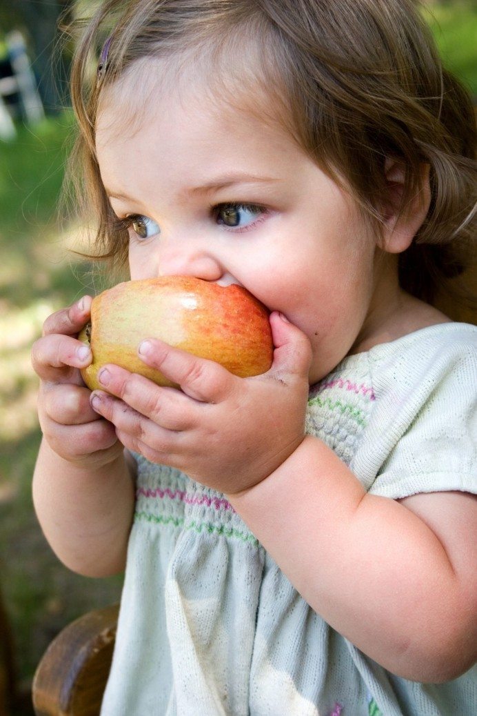 a dirty little girl eating a nice crispy apple
