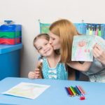 Mum kisses the daughter because she drew her beautiful